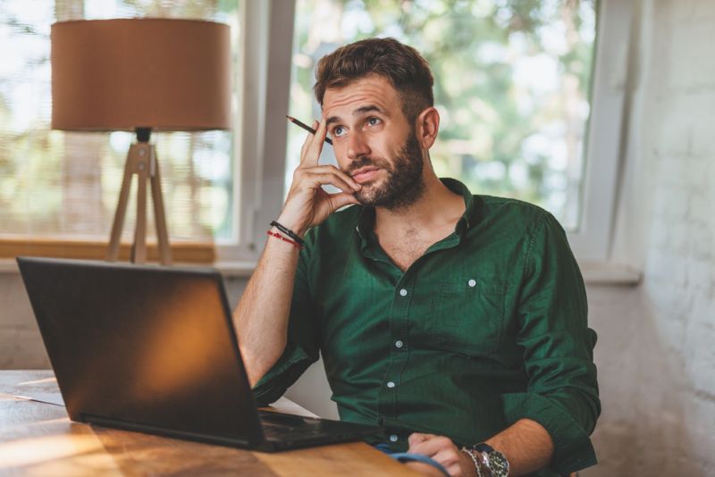 Puzzled man sitting and working on his laptop